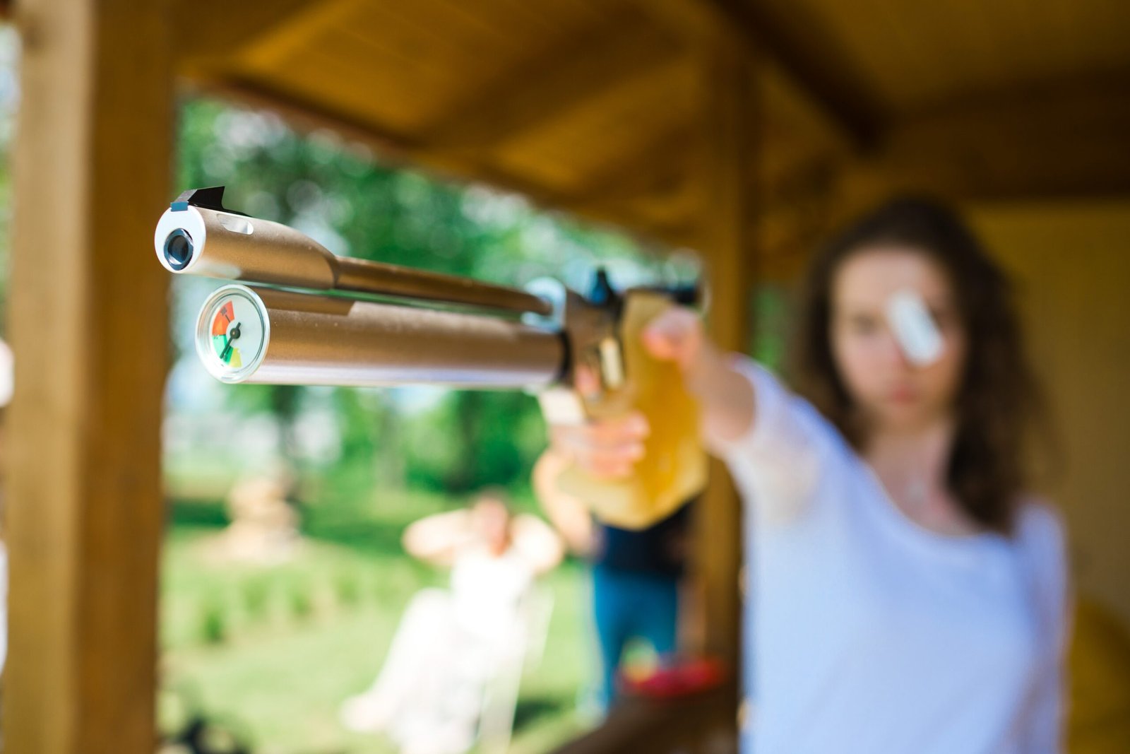 Aiming sport shooter, detail on compensator and air gauge on front of compressed air cylinder